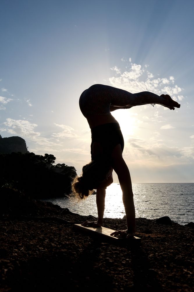 Silhouette of a woman practicing a variant of the handstand yoga