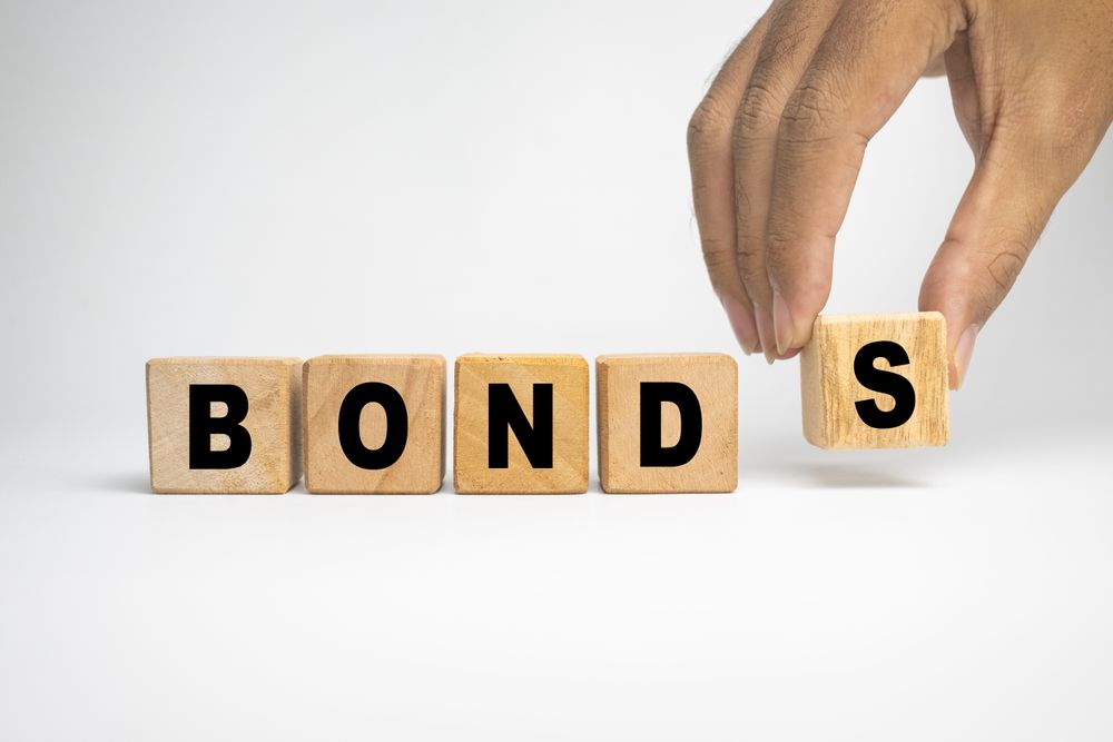 male hand putting wooden blocks with bonds word text