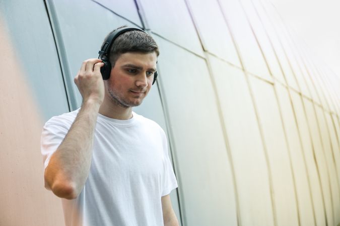 Young man in t-shirt listening to music in headphones