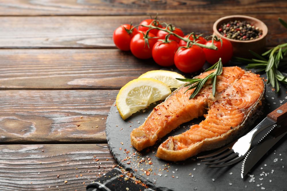 Composition with tasty grilled salmon on wooden background, space for text
