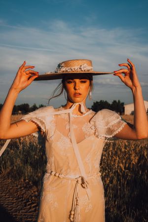 Woman in big round hat in middle of wheat field