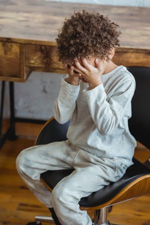 Young boy sitting on chair looking sad