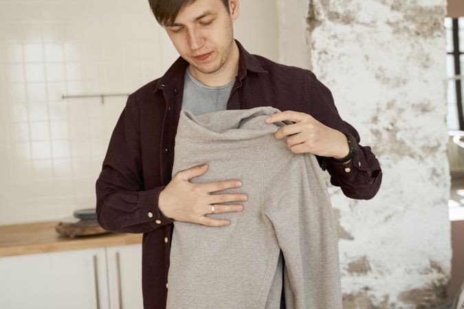 Man folding soft gray sweaters