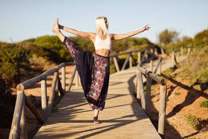 Woman stretching legs on wooden bridge