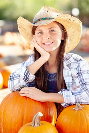 Girl Wearing Cowboy Hat Enjoying The Pumpkin Patch on a Sunny Fall Day.
