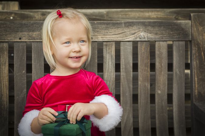 Adorable Little Girl Unwrapping Her Gift on a Bench
