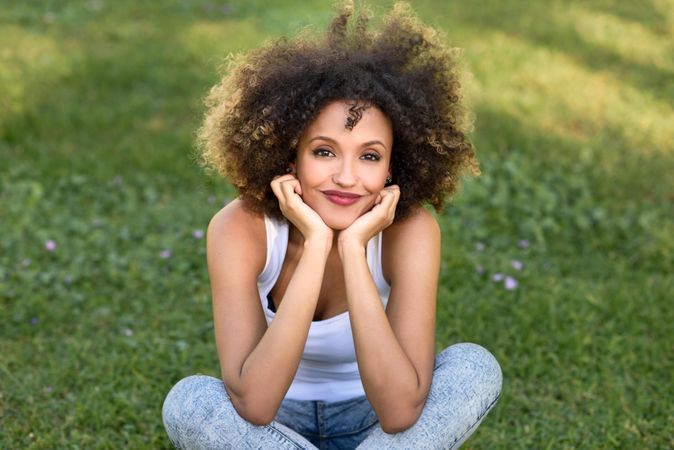 Black woman with afro hairstyle sitting cross legged in park