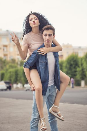 Teenage couple piggybacking in city