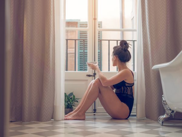 Woman in lingerie with coffee in hotel bathroom