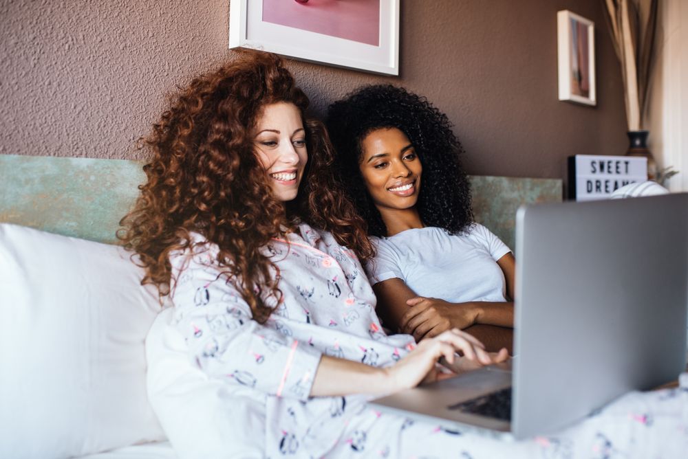 friends in bed entertained on their computer