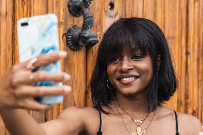 Cheerful Black woman taking selfie on smartphone