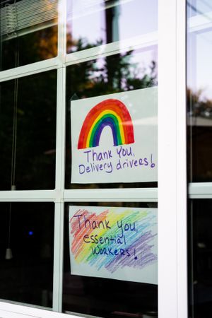Two handmade signs in house window thanking essential workers