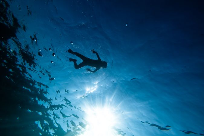 Unrecognizable preteen boy in flippers swimming underwater
