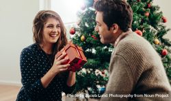 Man and woman exchanging Christmas presents in their living room 5ngkpQ