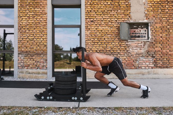 Black guy pulling weights in outdoor gym