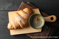 Board with croissant and mug of coffee on dark wooden background, top view 5oJ7y0