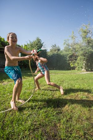 Little kids in swimwear having fun with splashing water