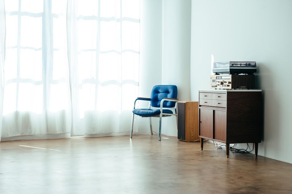 Large window with light curtains in urban loft  with vintage blue chair and stereo