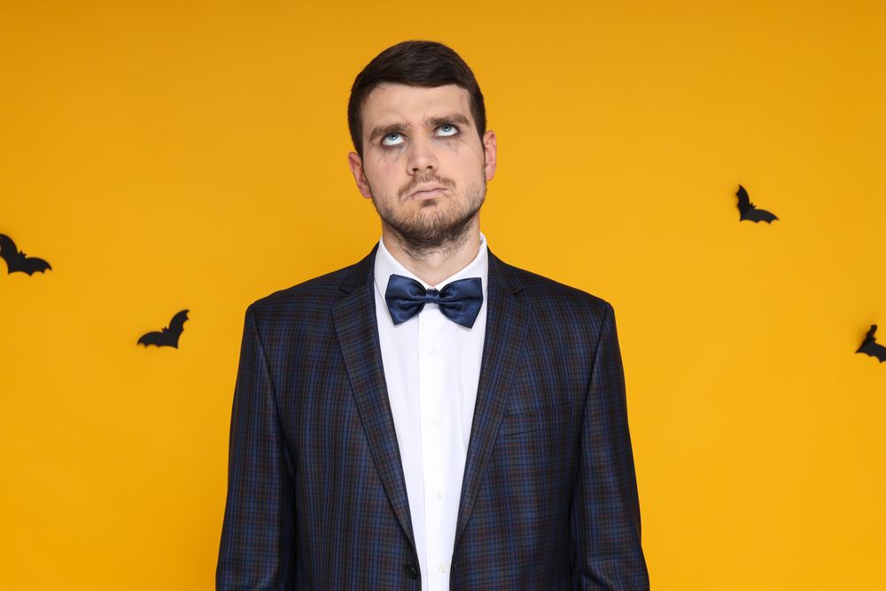 A man in a business suit with zombie makeup on a yellow background