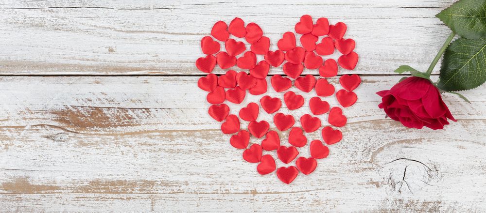 Filled red heart shapes and single rose on rustic wood