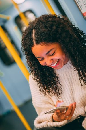Smiling Black woman using smartphone in transport
