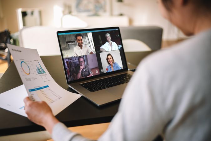 Woman holding a business report working at home having a video conference with colleagues