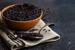 Organic dark rice in bowl with spoon on counter