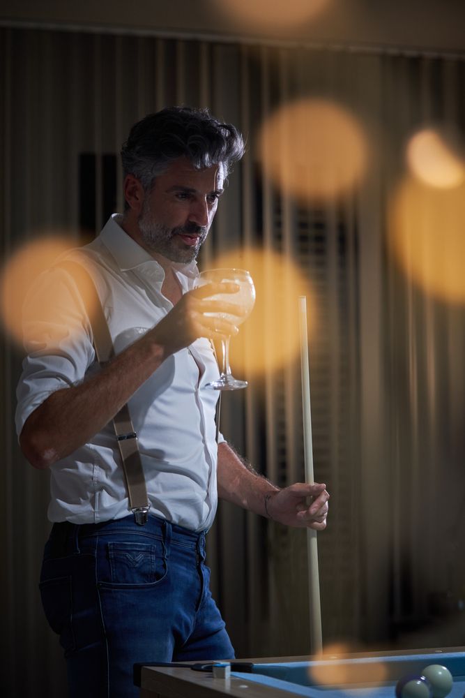 Adult male with cocktail playing billiards at home