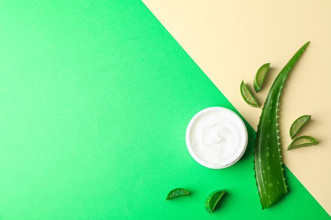 Aloe vera cream, leaves and slices on two tone background, space for text and top view. Natural treatment
