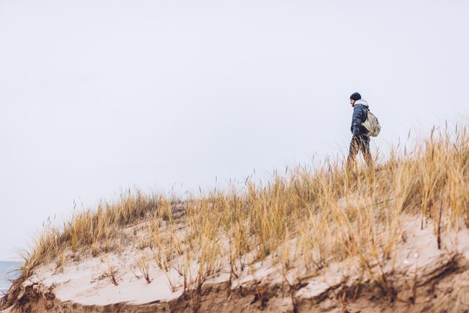 Man walking between sand field with dry grass