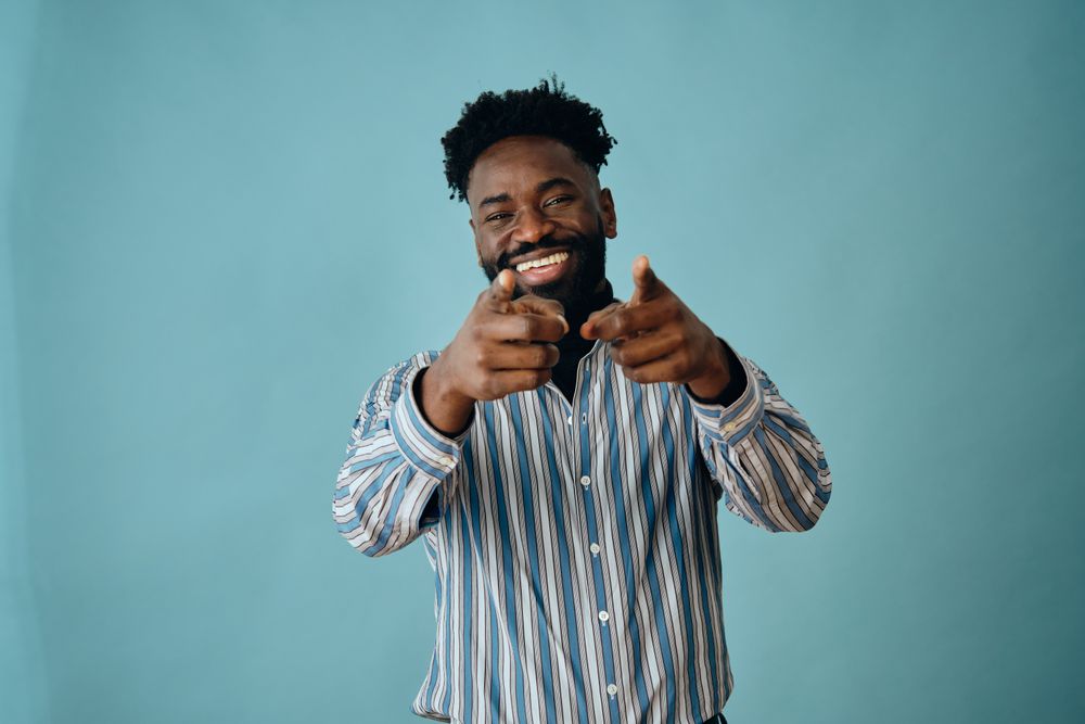 Smiling Black man in striped shirt pointing at the camera