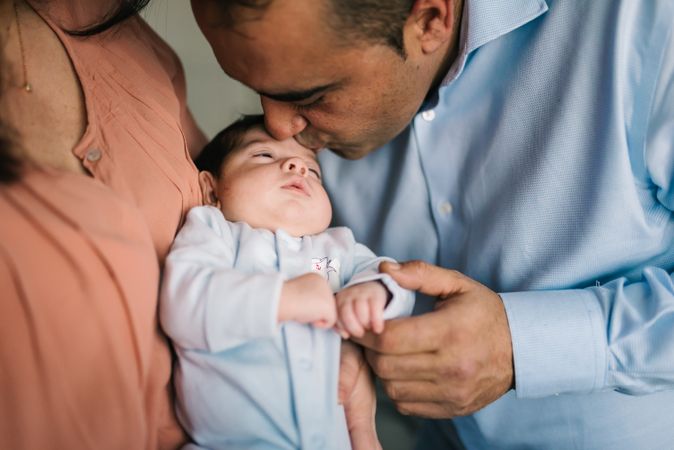 Happy family holding baby and standing at home together