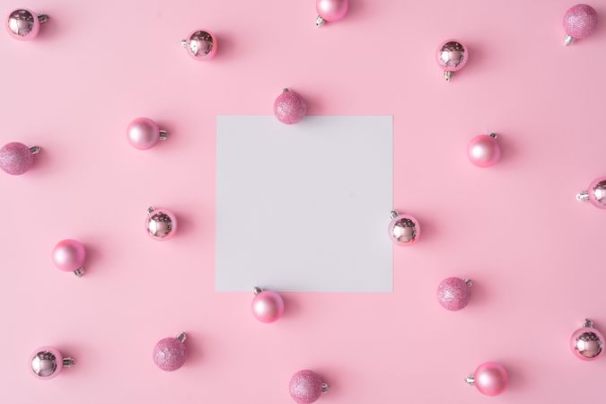 Different shades of pink baubles on a pink background with paper card