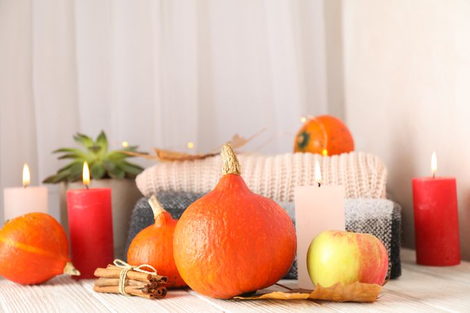 Pumpkins, clothes, leaves and candles on wooden background, copy space