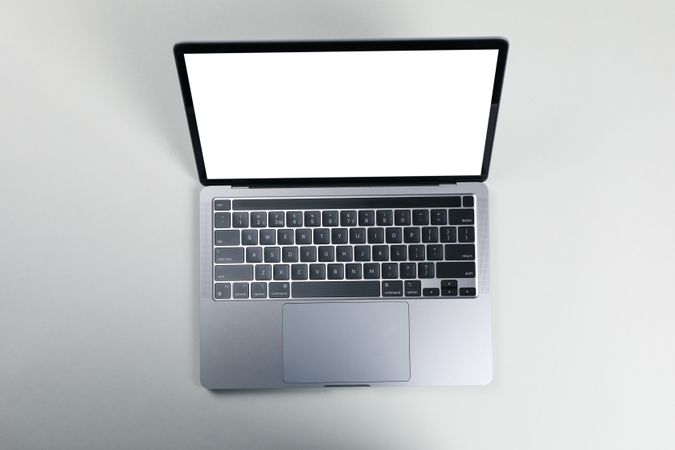 Top view of opened silver laptop with blank screen and keyboard on desk with copy space