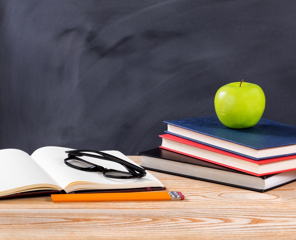 Back to school desk with stationery objects in front of erased chalkboard