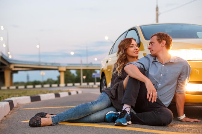 Couple sitting on road with yellow card