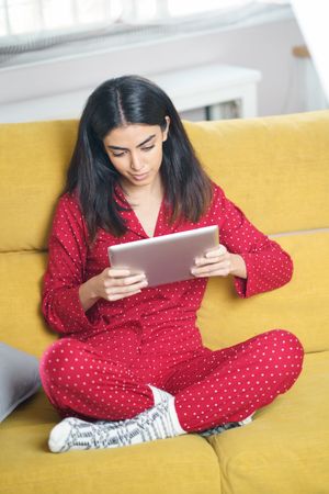 Vertical composition of female relaxing at home and using a tablet