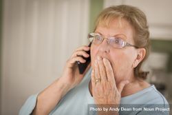 Shocked Older Adult Woman on Cell Phone in Kitchen 56GnKL