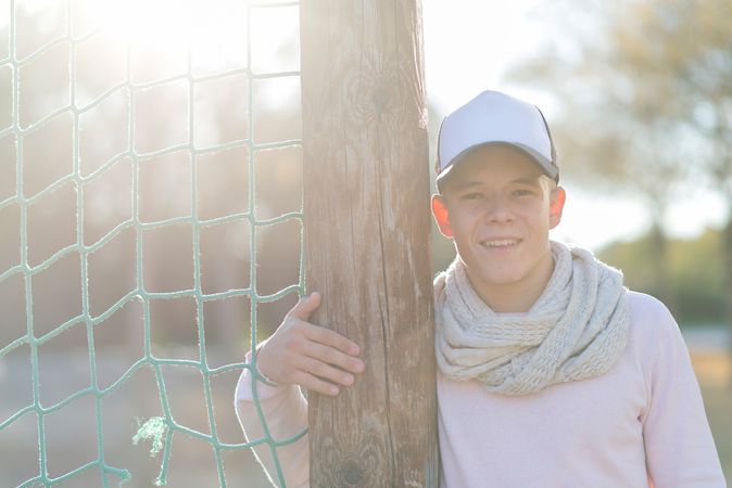 Teenage male wearing a cap leaning next to net