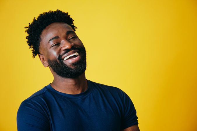 Portrait of happy Black man standing against yellow background