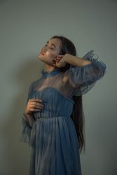 Woman in blue dress leaning on wall