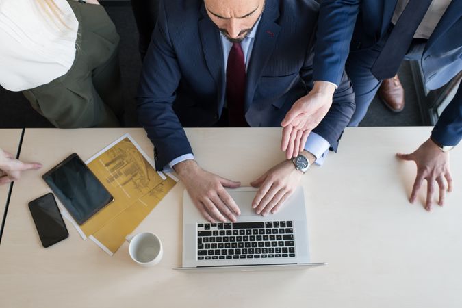 Stylish coworkers gathering around laptop in office