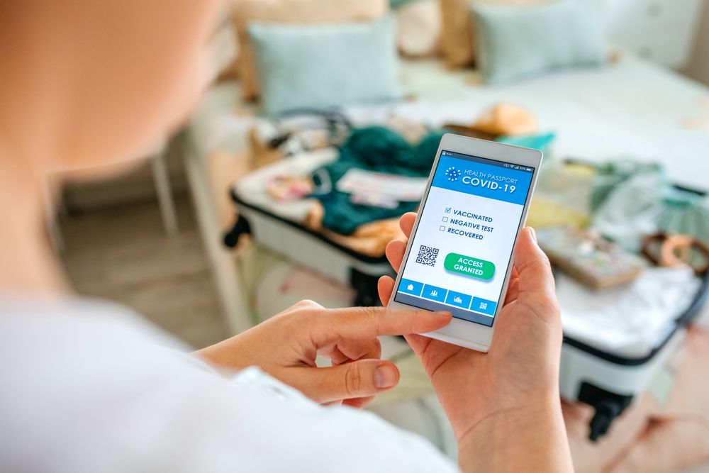Woman preparing the suitcase and looking digital green pass on the mobile
