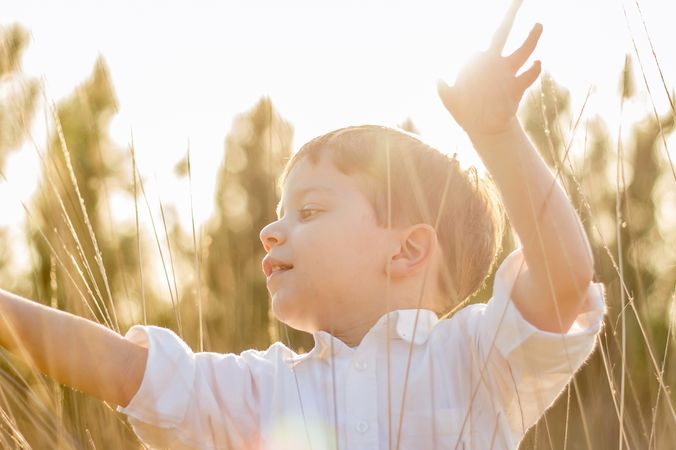 Kid in field playing with spikes at summer sunset