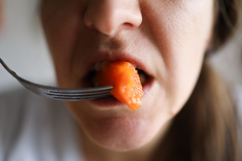 Close up Shot Of a Woman Chewing on a healthy Carrot.
