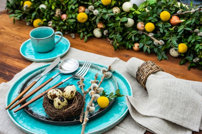 Easter table setting with bird nest & speckled eggs on teal plate