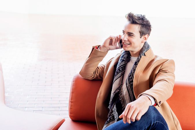 Happy man sitting outside talking on cellphone