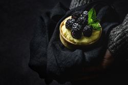 Hand holding a blackberry tartlet