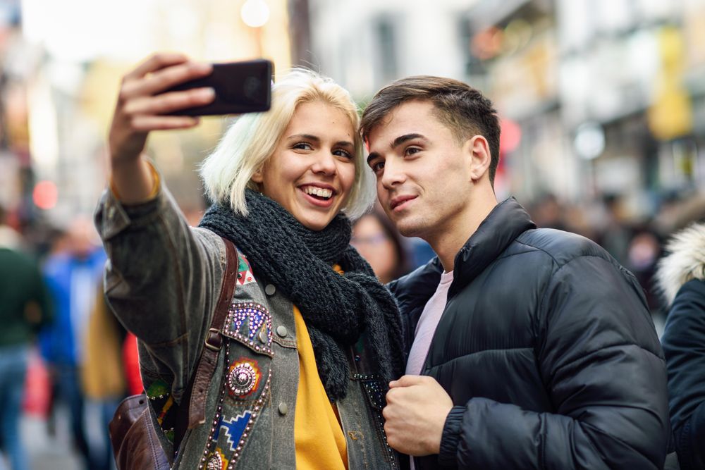 Female taking selfie with her male friend in UK street